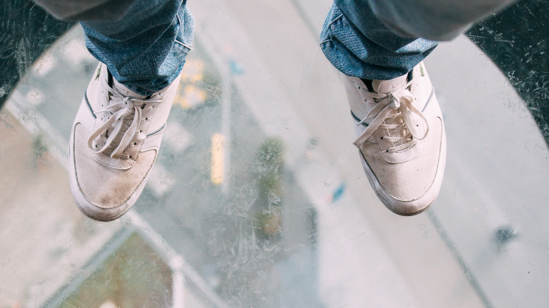 Feet on transparent surface high up. Photo by Oliver Schwendener on Unsplash